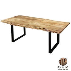 Op de afbeelding: Een rechthoekige eettafel met een natuurlijk lichtbruin houten blad met een boomstamrand en een zichtbare houtnerf. De tafel wordt ondersteund door twee zwarte metalen U-vormige poten. Een logo met de tekst OHM ORIGINAL HAND MADE is aanwezig.