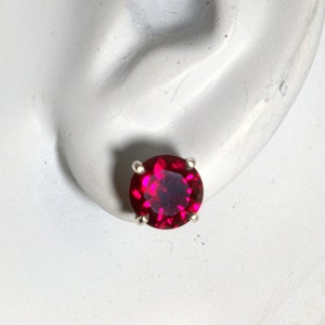 Op de afbeelding: Een paar robijnrode oorbel studs met een zilveren setting.