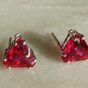 May include: A pair of silver earrings with triangular red gemstones.