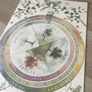 May include: A watercolour seasonal calendar with a circular design. The calendar shows the months and days of the week, with illustrations representing each season. The artwork includes butterflies, insects, and botanical elements.