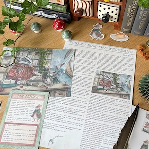 May include: A collection of printed paper stationery featuring the title Tales from the Woodland and Mr. Mouse, decorated with illustrations of a badger and a mouse in a cosy room, accompanied by a dark feather quill and small decorative mushroom figurines.