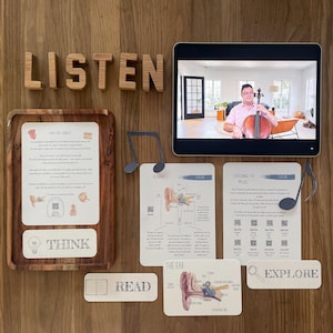 May include: A set of educational cards for children about listening to music. The cards feature illustrations of the ear, musical notes, and a person playing a cello. The cards also include the words "Listen", "Think", "Read", and "Explore".