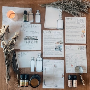Peut inclure: Un ensemble de flacons d'huiles essentielles, une loupe, une bougie, une plume et divers documents imprimés sur une surface en bois. Les documents comprennent des informations sur les huiles essentielles, leur histoire et leur utilisation. Le texte sur les documents comprend les mots "The Natural Apothecary", "Part One: Essential Oils", "Explore", "The History of Essential Oils", "Twine", "Think", "Distilled", "Video", "Aroma Zone", "Ancient Egypt", "Ancient Greece", "Ancient Rome", "Ancient India", et "The Process: Distillation".