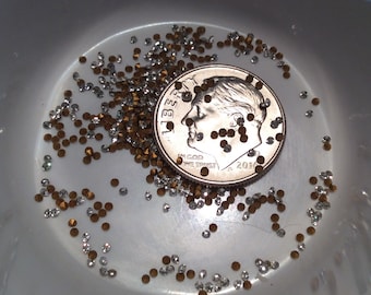 May include: A close-up of a US dime coin surrounded by small, clear and gold rhinestones. The coin is dated 2016 and has the words "In God We Trust" inscribed on it.
