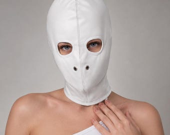 May include: A white full-head mask crafted from smooth material, featuring two oval-shaped eye openings and two small circular metal grommets positioned over the nose area. The mask has a central vertical seam and covers the entire head and neck.