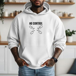 May include: White hoodie with a front pocket and a drawstring hood. The hoodie features the text "NO CONTROL" above a graphic of crossed chain links in black. The model is wearing blue jeans.