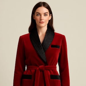 May include: A red velvet dressing gown featuring a black quilted collar and black trim on the pockets and belt. The gown is tied at the waist with a matching red belt. A luxurious garment.