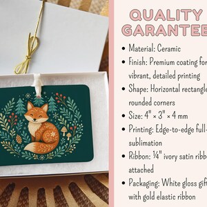 May include: A horizontal rectangular ceramic ornament with rounded corners, featuring a fox illustration surrounded by foliage on a dark green background. It includes a 0.64 cm ivory satin ribbon and comes in a white gloss gift box with a gold elastic ribbon.