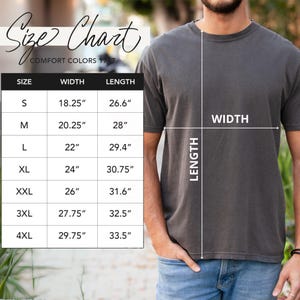 以下が含まれることがあります： Comfort Colors 1717 Tシャツのサイズチャート。Sから4XLまでのサイズの測定値がインチで表示されています。グレーのTシャツを着た人がいて、シャツの幅と長さが示されています。
