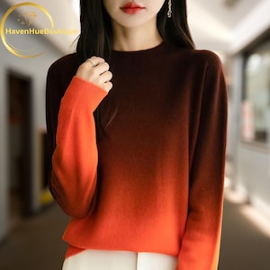 May include: A crew neck sweater with a color gradient from dark brown to orange. The sleeves and lower portion of the sweater are orange. The sweater has ribbed cuffs and a ribbed hem.