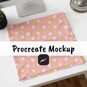 Può includere: Un tessuto rosa con un motivo di fette di limone gialle e fiori bianchi. Il testo "Procreate Mockup" è visualizzato sul tessuto. È visibile anche un quadrato nero con un'icona di pennello colorata.