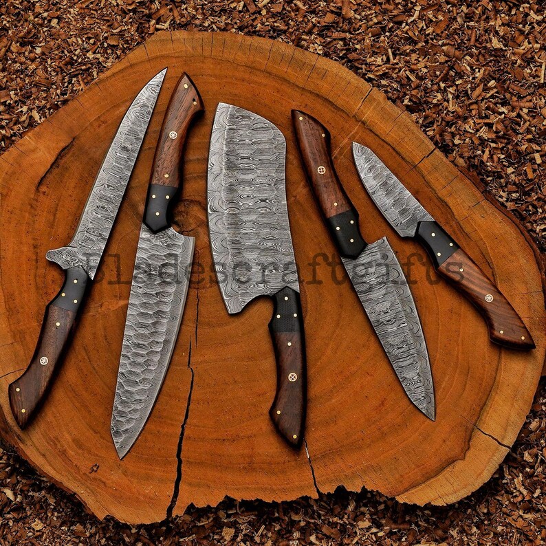 May include: A set of six Damascus steel kitchen knives with wooden handles and black accents. The blades have a unique patterned design. The knives are arranged on a round, wooden cutting board.