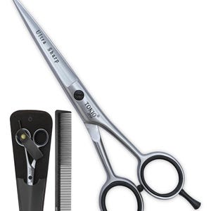 May include: Silver-coloured metal hair cutting shears with black finger rings and a finger rest. The blade is engraved with "Ultra Sharp" and "TOKIO IPN". Included is a black comb with "label.m" text and a black storage case containing a second pair of shears.