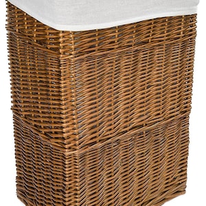 Puede incluir: Una cesta de mimbre marrón rectangular para la colada con tapa con bisagras. La cesta tiene un forro de tela blanca visible en la parte superior. El diseño tejido crea una superficie texturizada. Ideal para dormitorios y baños.
