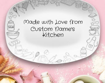 May include: White oval serving platter with a pink background. The platter has a border of sketched kitchen tools and the text "Made with Love from Custom Name's Kitchen" in the center. Baking-themed.