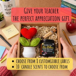 Puede incluir: Una caja de regalo con una flor de corazón rojo de ganchillo, una vela con una etiqueta que dice "Thank You Mrs. Mal for Helping Me Grow!" y un pequeño recipiente de vidrio con cerillas. La caja también incluye el texto "Give Your Teacher The Perfect Appreciation Gift".