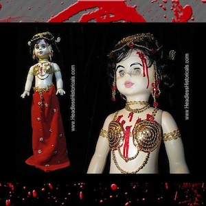 May include: A porcelain doll with a red and gold costume, a bloody face, and a crown of jewels. The doll is posed with its arms outstretched. The background is black with red splatter paint.