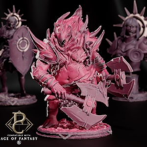 May include: A pink miniature figurine of a hulking, flame-headed warrior wielding a large double-bladed axe. The figure wears spiked shoulder armor and stands on a circular base. In the background, two other blurred figures are visible.