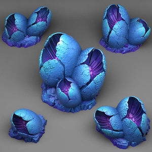 Op de afbeelding: Een verzameling fantasie-sculpturen die gebarsten, blauwe eieren met een getextureerd oppervlak uitbeelden. De binnenkanten zijn diep paars en de eieren rusten op een getextureerde, paarse basis. Het thema is fantasie of sciencefiction.