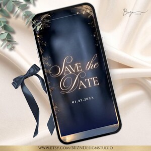 May include: A smartphone displays a digital invitation with the text "Save the Date" in elegant script. The background is a dark blue gradient with gold accents. A navy blue ribbon and greenery are in the foreground.