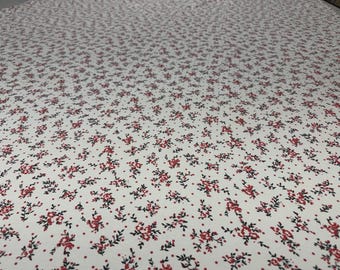 May include: White fabric with a repeating pattern of small red flowers and black leaves. The floral design is evenly distributed across the surface, creating a delicate and classic aesthetic. The fabric appears to be cotton or a similar material.