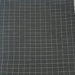 May include: Dark gray fabric with a white grid pattern. The fabric has a textured appearance with horizontal lines. The grid is made up of thin, white lines that intersect to form squares. The fabric is folded at the top right corner.
