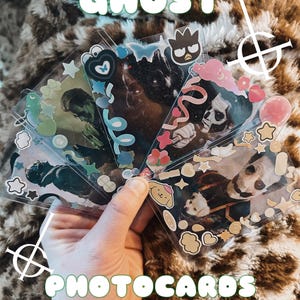 May include: A collection of rectangular trading cards featuring photographic portraits of individuals with theatrical makeup, decorated with various colorful stickers including stars, hearts, and cartoon characters, with the text GHOST PHOTOCARDS.