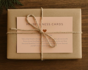 May include: A wrapped package with a light brown paper and a peach-colored card tied with twine. The card reads "MINDFULNESS CARDS" and includes instructions for breathing exercises. A small brown heart is visible.