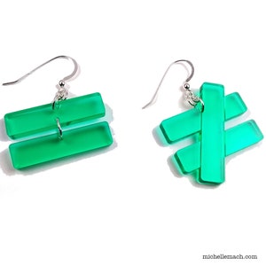 May include: A pair of green acrylic earrings. One earring is shaped like the equal sign and the other is shaped like the hashtag symbol.