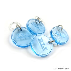 May include: Three blue plastic pet ID tags with silver rings. The tags are engraved with the names "Lily", "R.I.T." and "Lily".