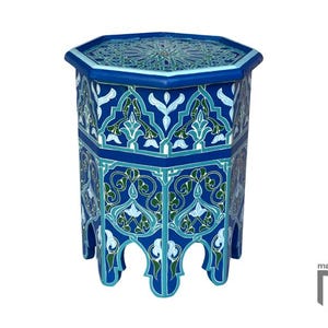 May include: An octagonal side table in shades of blue, teal, and white, featuring detailed geometric and floral patterns. The table has a decorative top and arched legs. The table is a decorative piece.