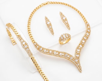 Sieradenset met baguette-stenen, verguld met 22 karaats goud: ketting, armband, oorbellen en ring.
