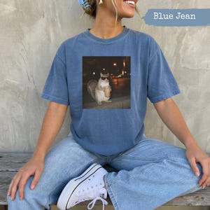 Squirrel wearing sunglasses holding iced coffee, displayed on a blue t-shirt.