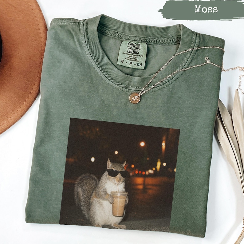 Moss green t-shirt with sunglasses-wearing squirrel holding a coffee cup.