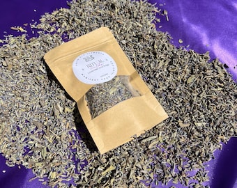May include: A small kraft paper bag filled with dried lavender and sage, with a white label that reads "RITUAL Lavender and Sage". The bag is surrounded by a pile of dried lavender on a purple satin surface.