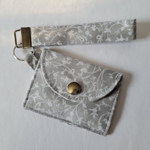 Mini llavero con tarjetero y diseño de vides blancas sobre fondo gris