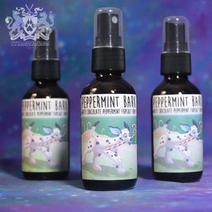 May include: Three glass bottles with black spray tops and labels. The labels are white with green and blue illustrations of a dog with a candy cane. The text on the labels reads "Peppermint Bark White Chocolate Peppermint Fursuit Spray".