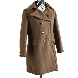 May include: A brown double-breasted coat with gold-colored buttons. The coat has a classic design with a notched collar and two front pockets. The coat is displayed on a mannequin.