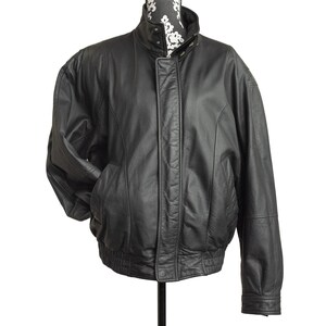 May include: A black leather jacket with a stand-up collar and a zipper closure. The jacket has two front pockets and a ribbed hem. The jacket is displayed on a mannequin.