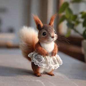 May include: A handmade squirrel figure with a fluffy tail and a white lace skirt. The squirrel has brown fur, a white chest, and pointed ears. The figure is posed on a light grey surface.