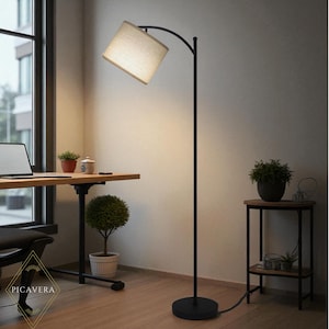 May include: A black arc floor lamp with a beige rectangular lampshade. The lamp is positioned next to a wooden desk with a laptop and potted plants. The lamp has a round base and a curved arm.
