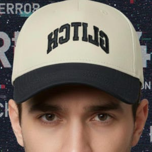 May include: A cream-coloured baseball cap with a black brim. The cap features the word "ERROR" in black, stylised text. The background has a dark blue digital glitch design with the words "ERROR", "GLITCH", and "DATA".