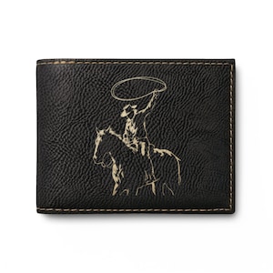 Puede incluir: Cartera de cuero negro con una ilustración de vaquero. La cartera presenta una imagen detallada de un vaquero a caballo, lazando un toro. Los bordes están cosidos con un hilo beige en contraste.