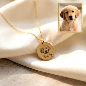 Op de afbeelding: Een goudkleurige ketting met een ronde hanger voorzien van een lasergegraveerde illustratie van een hondengezicht en de naam Buddy in script. Een klein kader toont een foto van een golden retriever puppy die bij de gravure past.