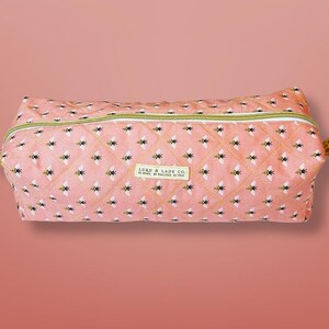 May include: A pink quilted pencil case with a repeating pattern of bees. The case has a yellow zipper and a small label that reads "LORD & LADY CO."