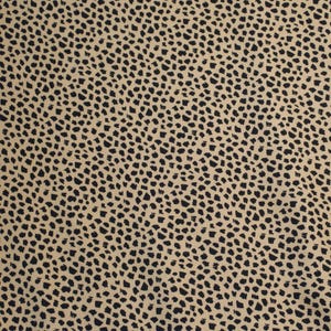 May include: A close-up of a fabric with a tan background and a repeating pattern of black, irregular shapes. The shapes are small and densely packed, creating a speckled appearance across the material.