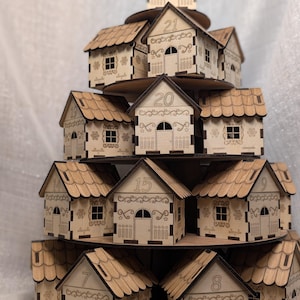 May include: A tiered wooden advent calendar in the shape of a Christmas village. The natural wood houses are numbered and arranged on circular platforms. Each house has a door and window, with decorative cut-out details.