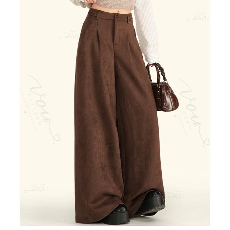 May include: High-waisted wide-leg trousers in a solid dark brown colour. These trousers feature a structured waistband with a single button closure, a front zip fly, and subtle pleats at the waistline, falling into a loose, floor-length silhouette.