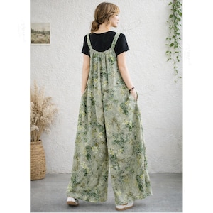 May include: A sleeveless, wide-leg jumpsuit featuring a light green base with an all-over botanical print of leaves and flowers in shades of green and yellow, worn over a plain black short-sleeved t-shirt with a round neckline.