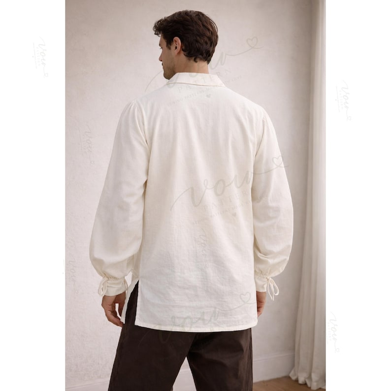 May include: A long-sleeved, off-white shirt featuring a fold-over collar, a button-down front, and gathered cuffs with ties at the wrists. The shirt has a straight hem with side slits and is paired with dark brown trousers.
